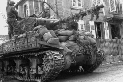 Unbelievable Grit: 14th Armored Division Tankers Risk It All Navigating a Booby-Trapped Battlefield in France—Inside the Sandbag-Fortified Sherman Tank as They Dodge Deadly Wires at Rittershoffen, March 1945. What Dangers Did These Brave Soldiers Face in the War’s Final Throes?