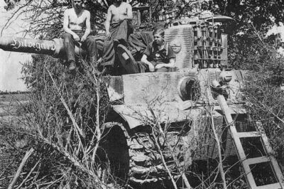 WWII Eastern Front Snapshot: Tiger I Tank #305, Nicknamed ‘Hildegard,’ with a Crewman of the 3rd Company, schwere Panzer-Abteilung 502 — Photographed in the Leningrad Sector, June 1944, This Iconic German Heavy Tank Symbolized the Fearsome Power of the Wehrmacht’s Armored Forces During One of the War’s Deadliest Campaigns.