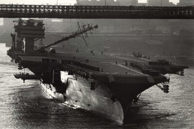 USS Constellation (CV-64) passing under the Brooklyn Bridge with her mast folded down, 1962.